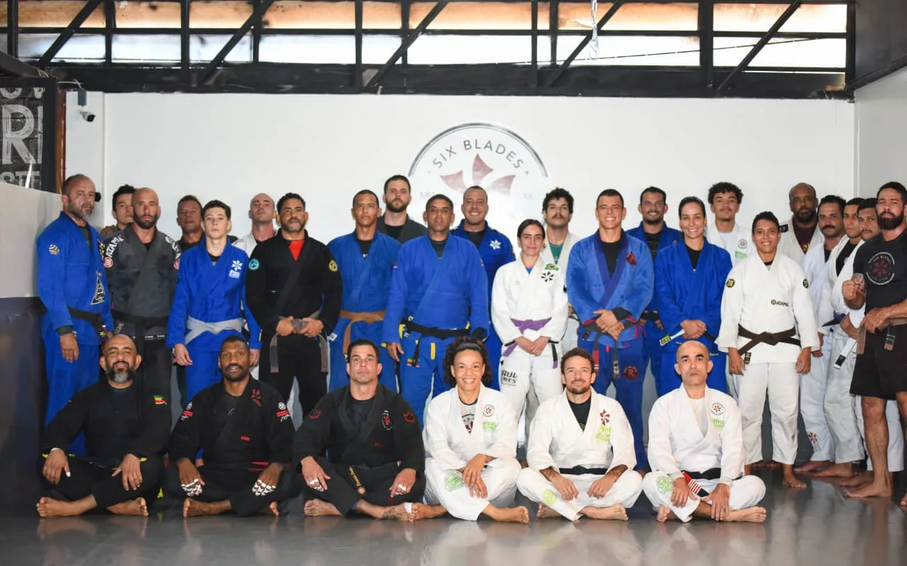Equipe completa da Six Blades Sudoeste reunida diante do brasão da academia